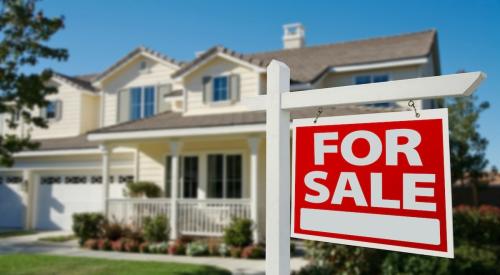 A home with a red "For Sale" sign in the front yard