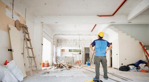 A man in a yellow hard hat looks over home renovation work 