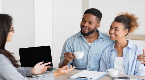 A Millennial couple speaks with a real estate agent about purchasing a home