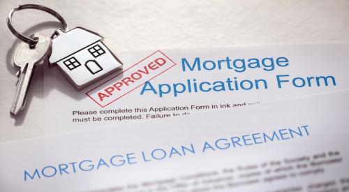 A mortgage loan application with a stamp of approval and a set of house keys sitting on top of it