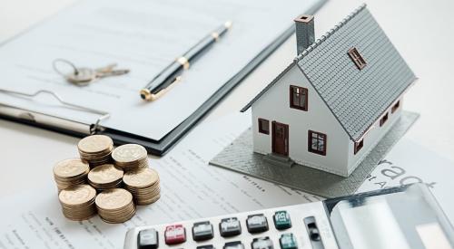 Shown is a table with a mortgage agreement, model home, calculator, and several stacks of coins.