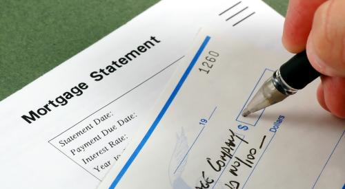 A closeup image of a hand writing out a check to a mortgage company