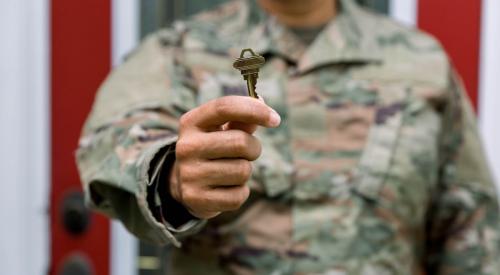 A man in a U.S. Army uniform holds up a key to a new home