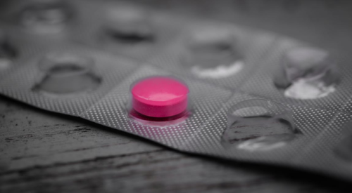 Pink opioid pill in pack of empty pill tabs