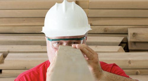 Construction worker sizes up lumber for building