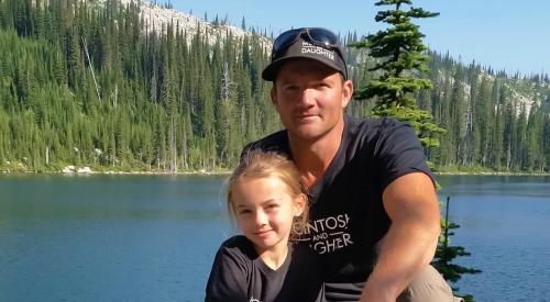 Man and daughter wearing matching shirts by a lake