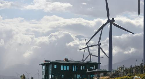 Modern farmhouse on hill with windmills in back