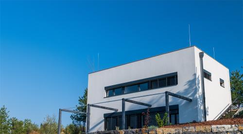 Modern, white, cube, elegant, minimalist style passive house with large panoramic windows, grey shutters in maintained garden