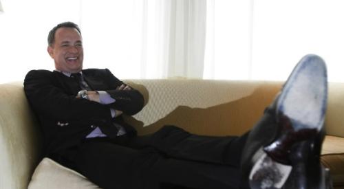 Actor Tom Hanks sitting on a sofa with his feet up, relaxing