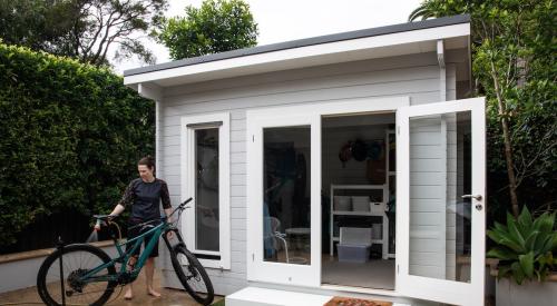 Woman washing a bike next to an accessory dwelling unit (ADU) in backyard