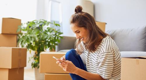 A woman sits on the floor, surrounded by boxes.