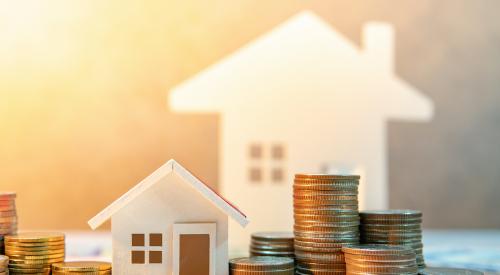 Two house figurines with stacks of coins