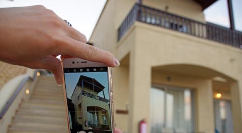 Woman taking a photo of house with cell phone