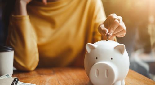 Woman putting coin in piggy bank