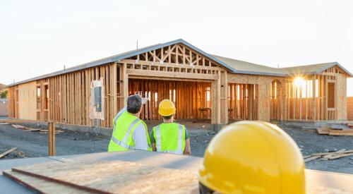 Two home builders looking at a house mid-construction