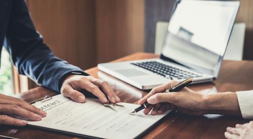 Two pairs of hands reviewing contract paperwork