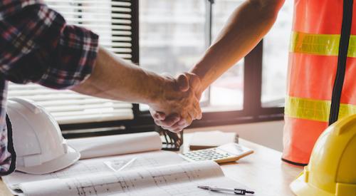 Two men shake hands, one wears builder vest 