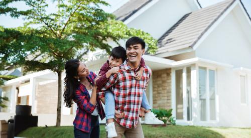 Parents with child smiling in front of home