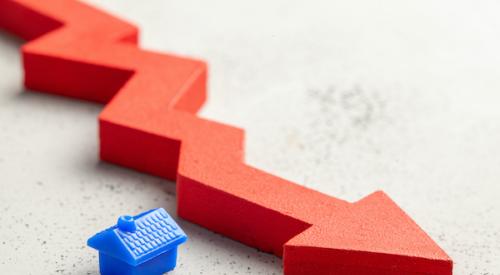 Small house figurine next to a large red decreasing line graph