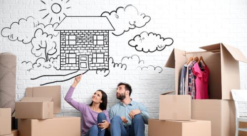 Couple sits on floor with moving boxes as they dream about their new home