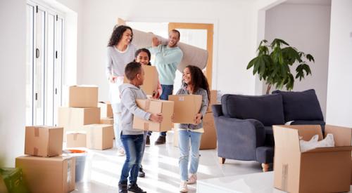 Family smiling while holding moving boxes