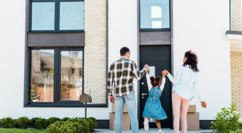 Parents swinging child in front of new home