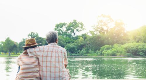 An older couple sitting by a lake