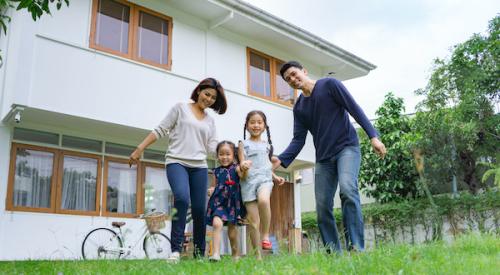 Parents with two children smiling in front of their home