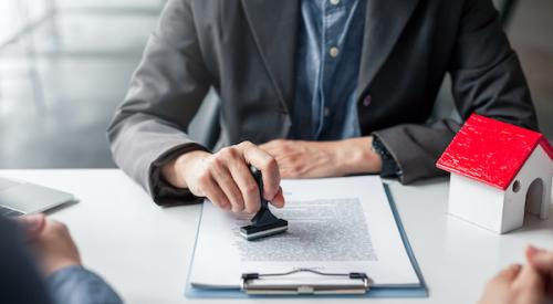 Business man stamping mortgage application in front of two clients