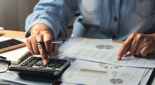 Person working with calculator and money to determine a budget