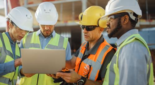 Group of home builders looking at a laptop screen on a jobsite