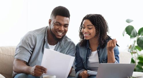 Happy couple smiling while looking at paperwork