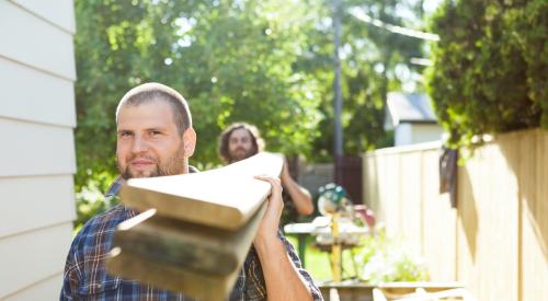 Two tradesmen carrying lumber