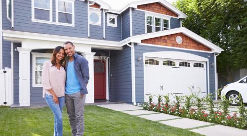 A couple stands in front of a house