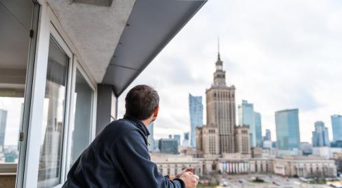 Man in apartment looks at city skyline