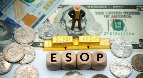 Business leader figurine standing on money in front of gold bars and letters spelling 'ESOP'