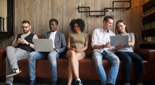 Five seated Millennials with smart phones and laptops