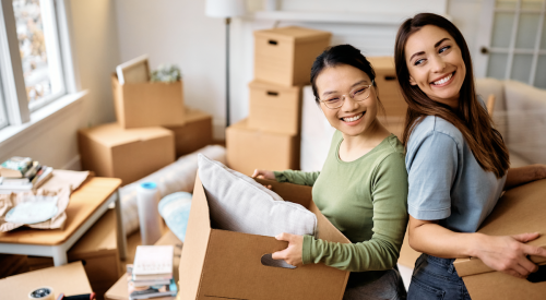 Two Gen-Z renters moving cardboard boxes into new apartment