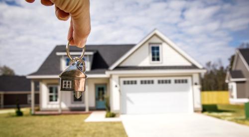 Person holds keys in front of house