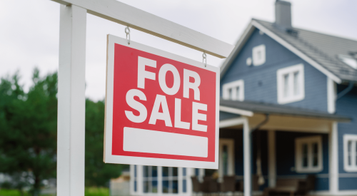 Blue and white single-family home with for-sale sign in front yard