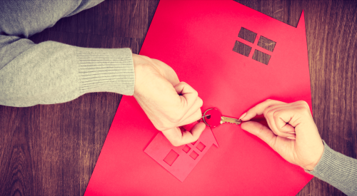 Homeowner hands holding onto key over red house with low mortgage