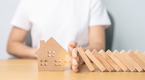 Falling dominoes stopped from toppling wooden house