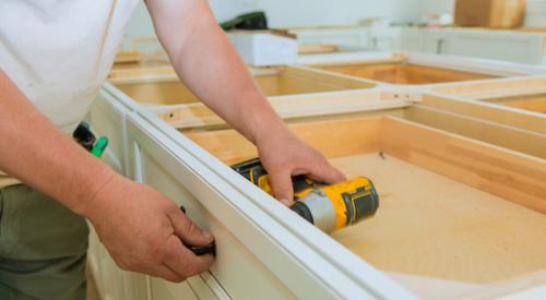 Man using power drill to assemble kitchen cabinet