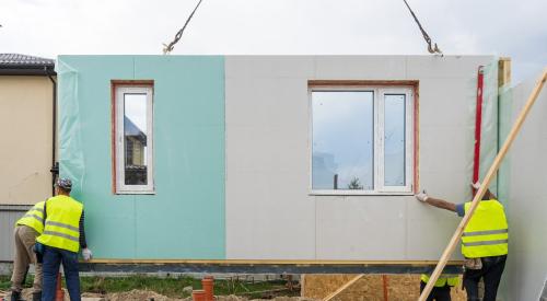 Workers on construction site installing modular home panels