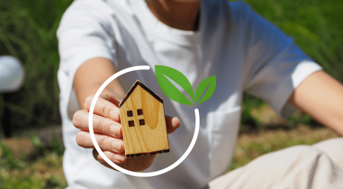 Hand holding model of house to show net-zero goal for homes