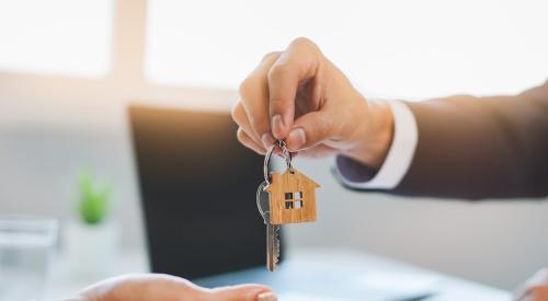 A man hands a woman a set of keys.