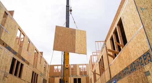 Crane hoisting a wall prefab panel