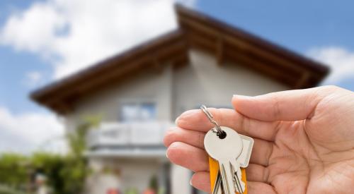 New homebuyer holds keys in front of house