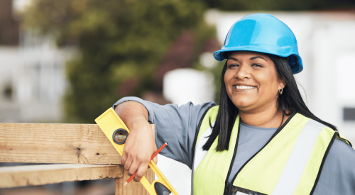 Smiling woman contractor wearing hardhat on construction site