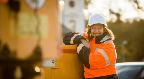 Smiling woman construction worker wearing white hardhat on jobsite